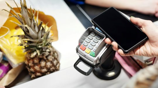 Mobile phone being used to make EFTPOS purchase. Newsreel