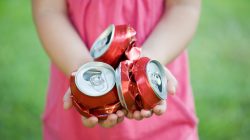 Girl holding crushed cans. | Newsreel