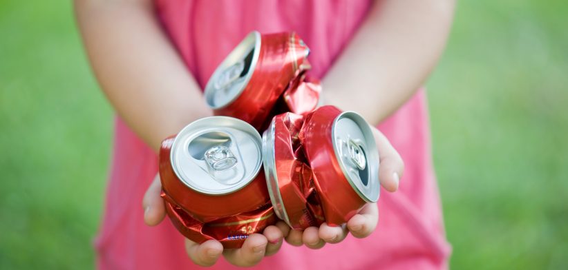 Girl holding crushed cans. | Newsreel