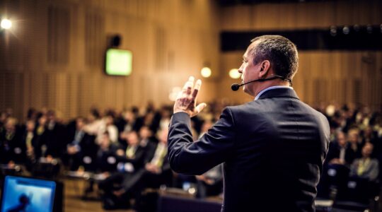 Man talking to crowd at conference. | Newsreel