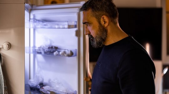 Depressed man looking into fridge. | Newsreel