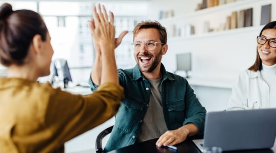 Workers high five in office. | Newsreel