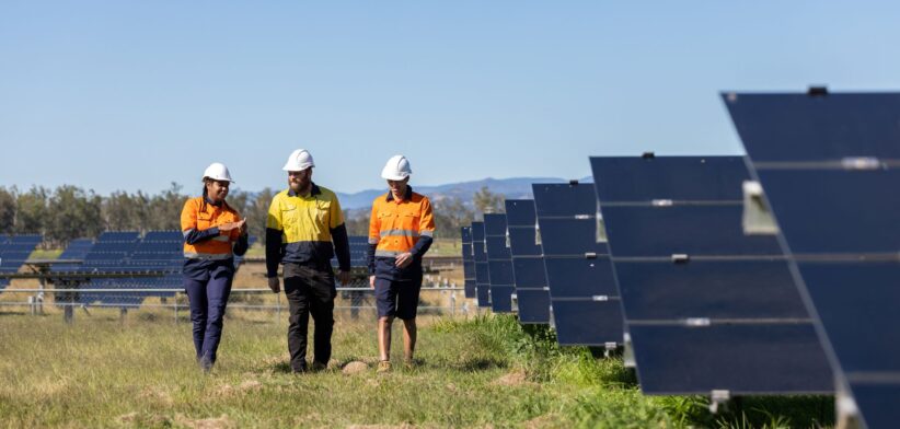Thee technicians, two Aboriginal, walk in solar farm. | Newsreel