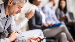 Man looking at phone in waiting room. | Newsreel