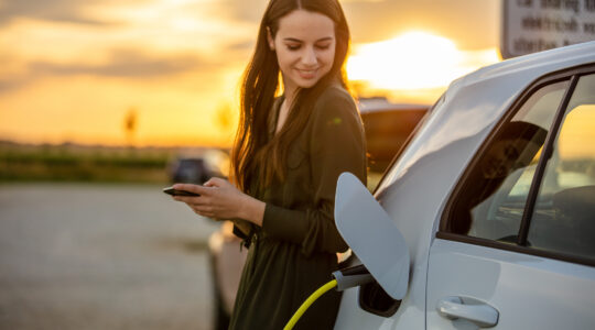 Woman charging electric vehicle. | Newsreel