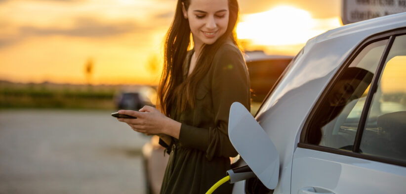 Woman charging electric vehicle. | Newsreel