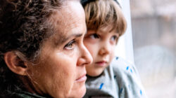 Worried woman and child gaze out window. | Newsreel