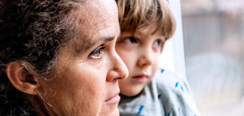 Worried woman and child gaze out window. | Newsreel