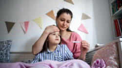 Women checks sick child's temperature. | Newsreel