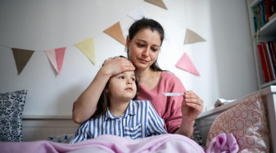 Women checks sick child's temperature. | Newsreel