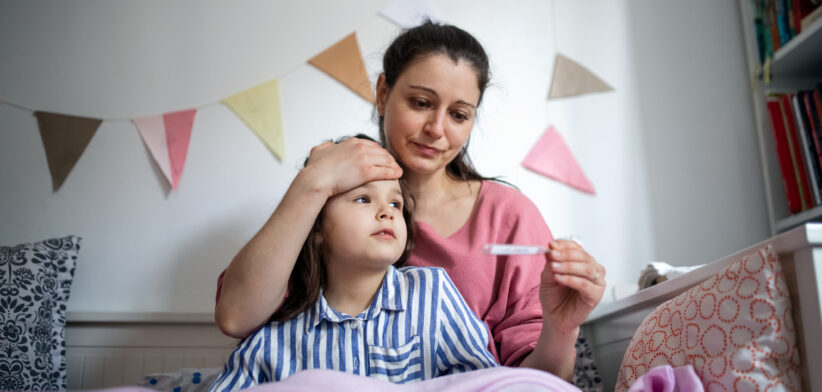 Women checks sick child's temperature. | Newsreel