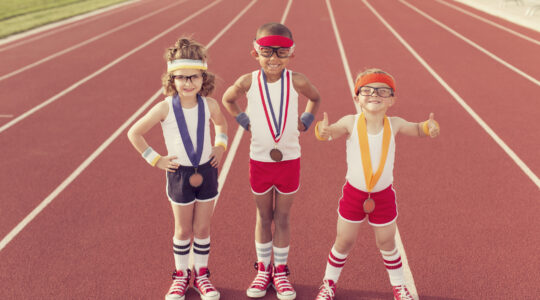 Children sporting medals on running track. | Newsreel