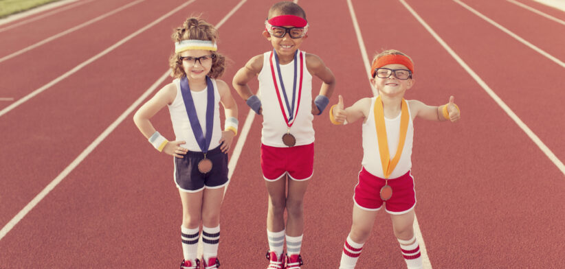 Children sporting medals on running track. | Newsreel