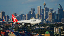 Qantas plane flying with city skyline in background. | Newsreel