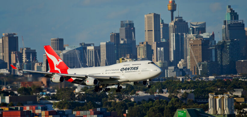 Qantas plane flying with city skyline in background. | Newsreel