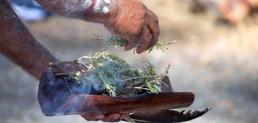 Aborigine with plant at smoking ceremony. | Newsreel
