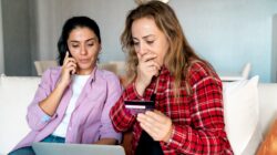 Woman on phone and woman shocked looking at credit card. | Newsreel