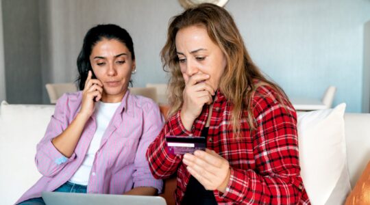 Woman on phone and woman shocked looking at credit card. | Newsreel