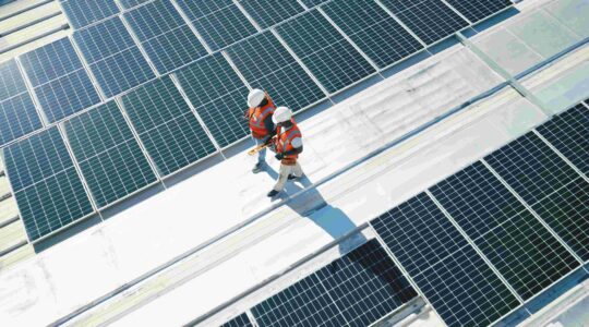 Men walking on roof with solar panels. | Newsreel