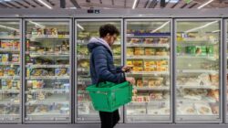 Man in supermarket looking at phone. | Newsreel