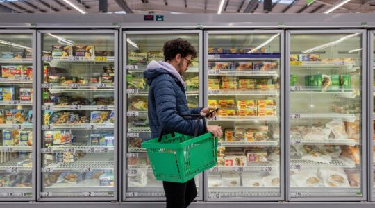 Man in supermarket looking at phone. | Newsreel