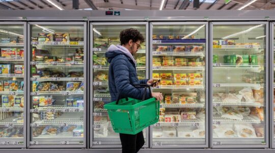 Man in supermarket looking at phone. | Newsreel