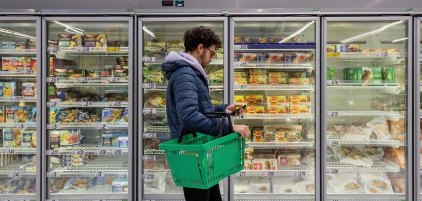Man in supermarket looking at phone. | Newsreel