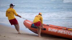 Queensland surf lifesavers pulling boat out of water. | Newsreel