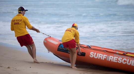 Queensland surf lifesavers pulling boat out of water. | Newsreel