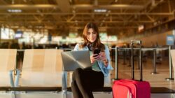 Woman in airport on laptop and phone. | Newsreel