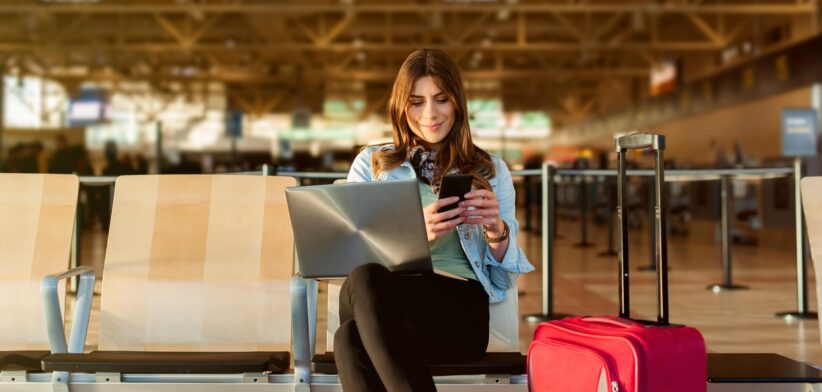 Woman in airport on laptop and phone. | Newsreel