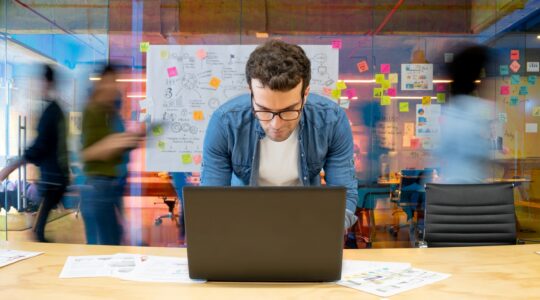 Man on computer with people rushing in background. | Newsreel