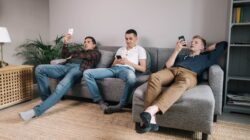 Three men sitting in couch on phones. | Newsreel