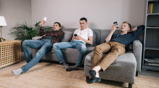 Three men sitting in couch on phones. | Newsreel