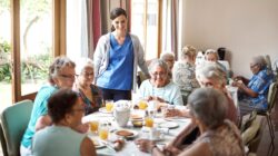 Carer with elderly in aged care home dining room. | Newsreel