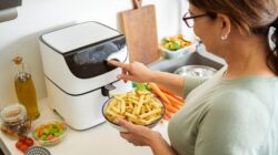 Woman setting air fryer to cook chips. | Newsreel