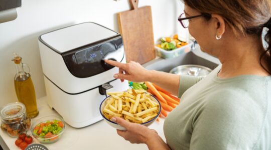 Woman setting air fryer to cook chips. | Newsreel