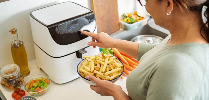 Woman setting air fryer to cook chips. | Newsreel