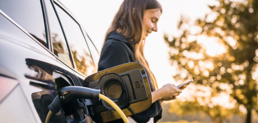 Woman waiting for electric car to charge. | Newsreel