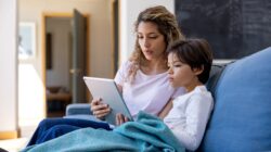 Woman and child on couch looking at tablet computer. | Newsreel