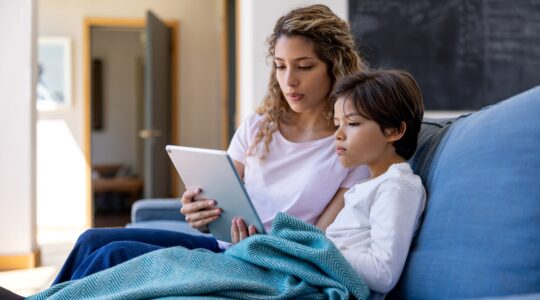 Woman and child on couch looking at tablet computer. | Newsreel