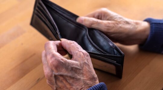 Aged man looking at empty wallet. | Newsreel