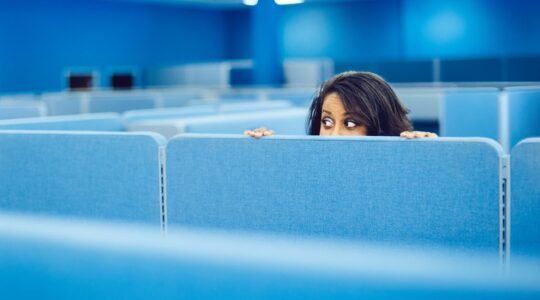 Woman peering over dividers at work. | Newsreel