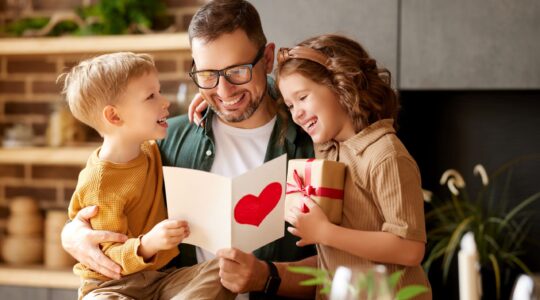 Dad looking at Father's Day card with children. | Newsreel