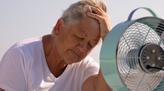 Heat stressed elderly woman in front of fan. | Newsreel