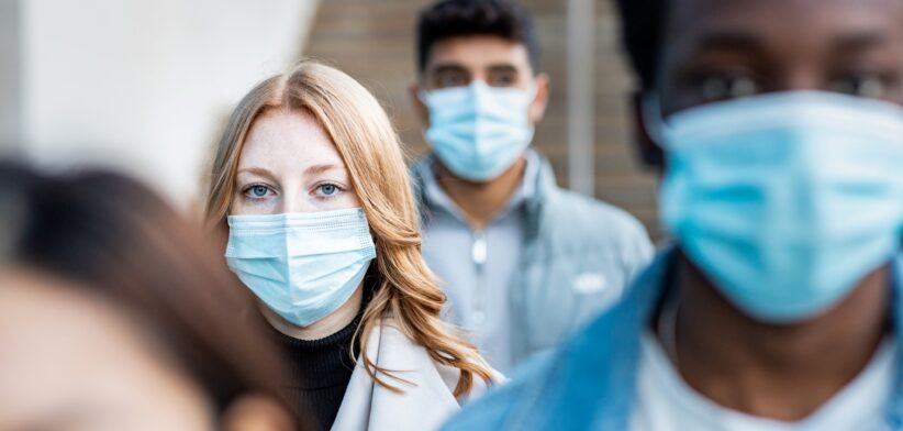 Woman in crowd wearing mask. | Newsreel