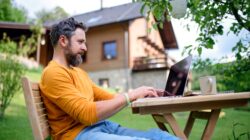 Man working in back yard on laptop. | Newsreel