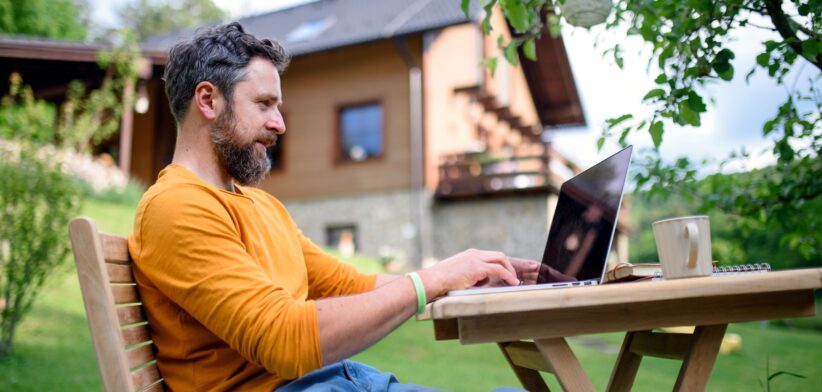 Man working in back yard on laptop. | Newsreel