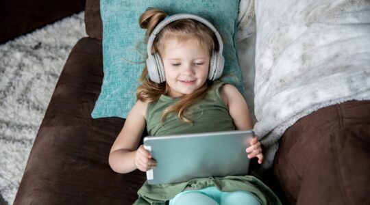 Child watching content on tablet with headphones.