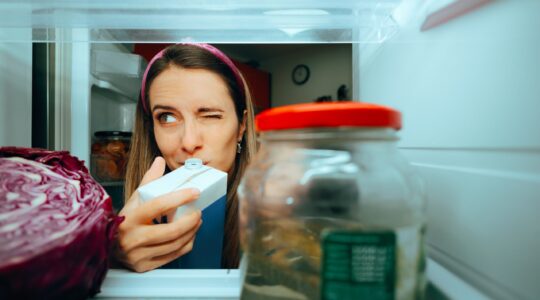 Woman testing milk in fridge. | Newsreel